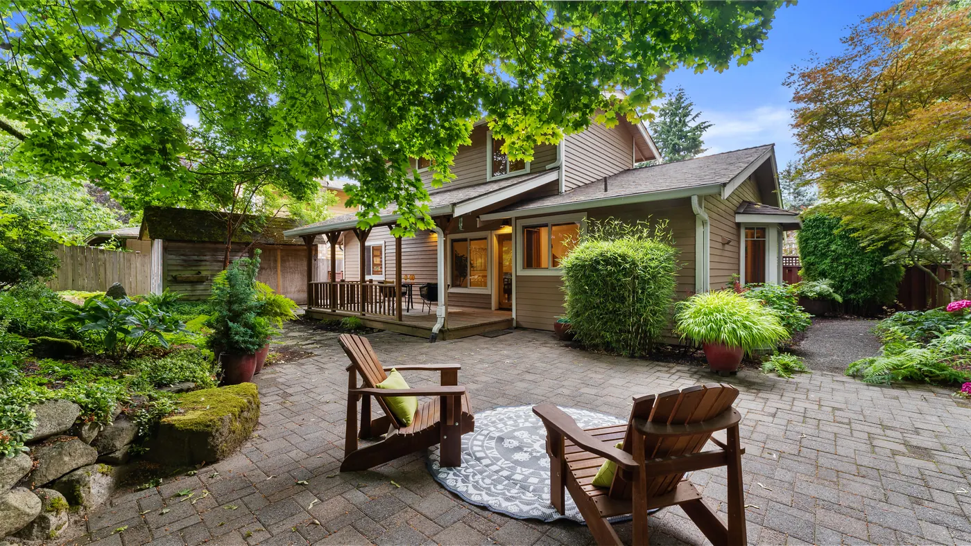 Garden patio with Adirondack chairs behind a two-story home