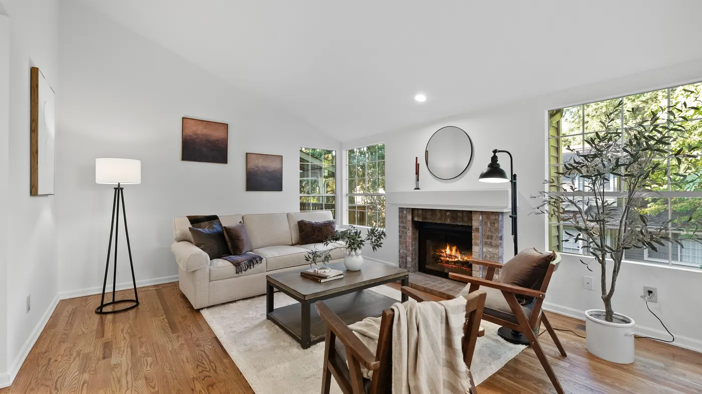 Bright staged living room with a fireplace and vaulted windows